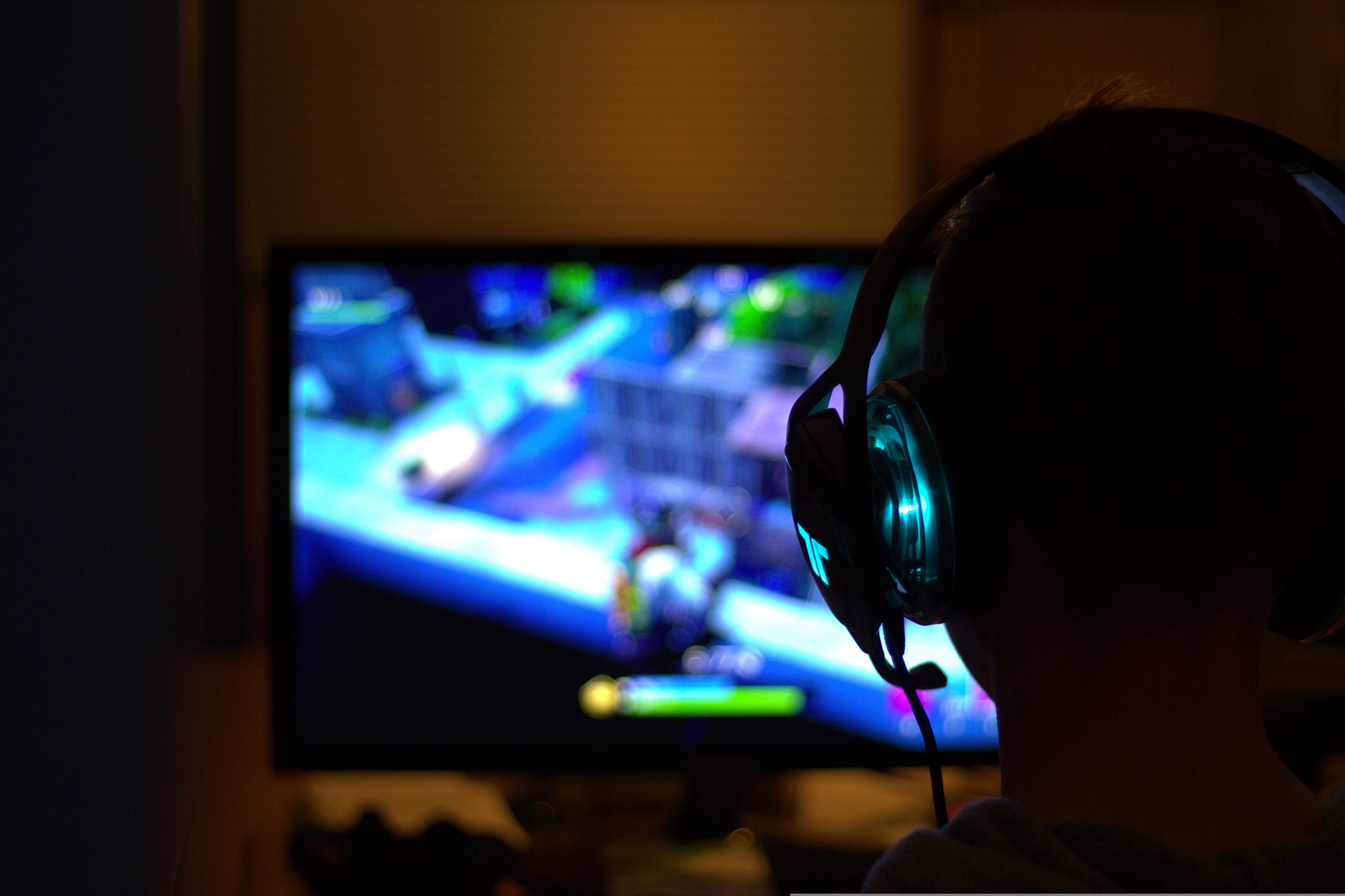 A gamer using headphones is playing on a TV.